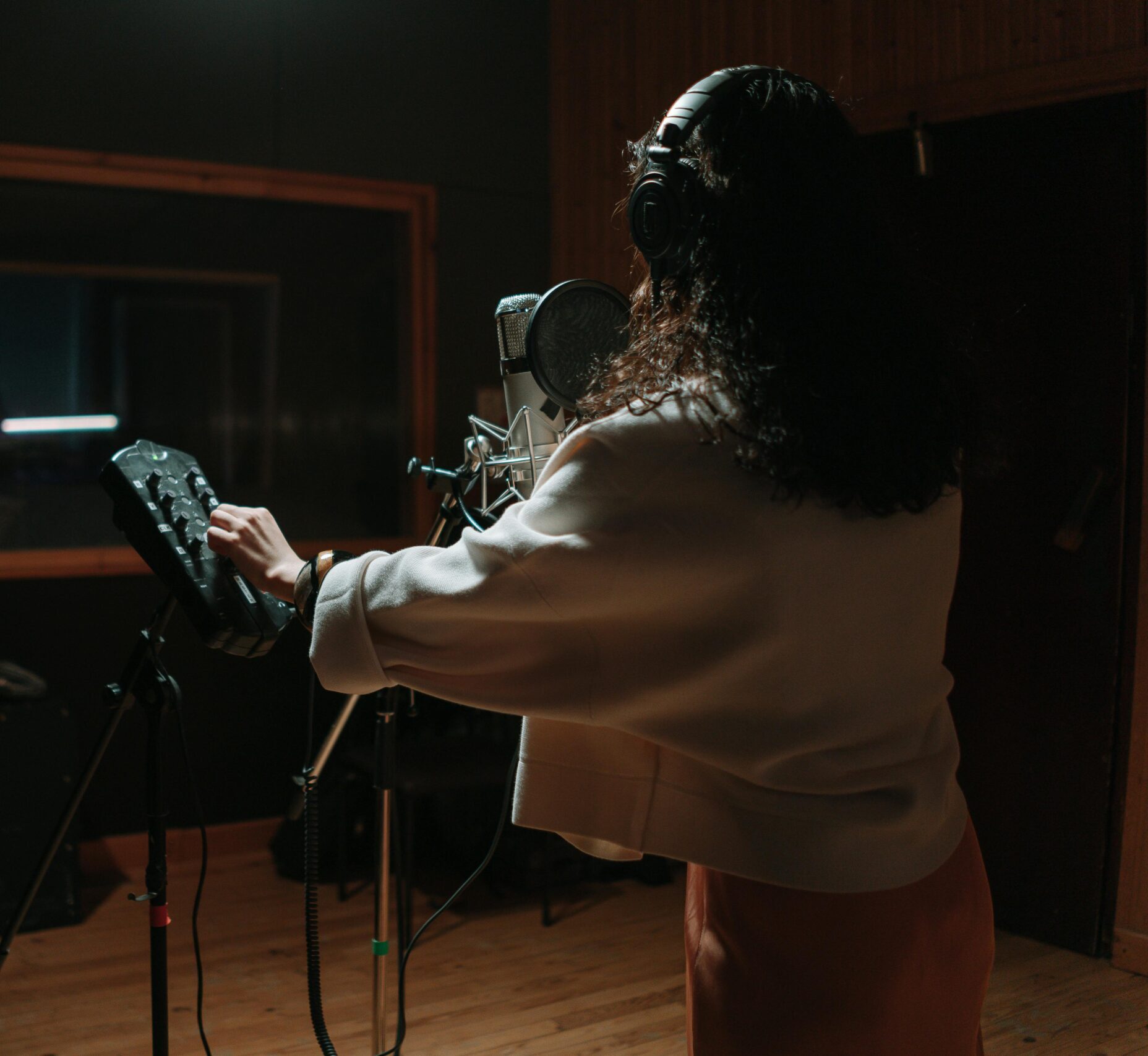 Woman singing in a professional music studio with condenser microphone.